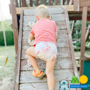 Toddler in sustainable cloth diaper climbs on a playground