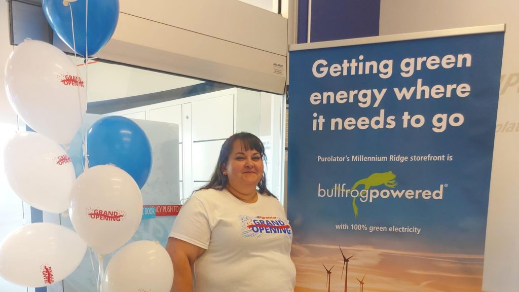Woman standing beside a Bullfrog Power sign and balloons