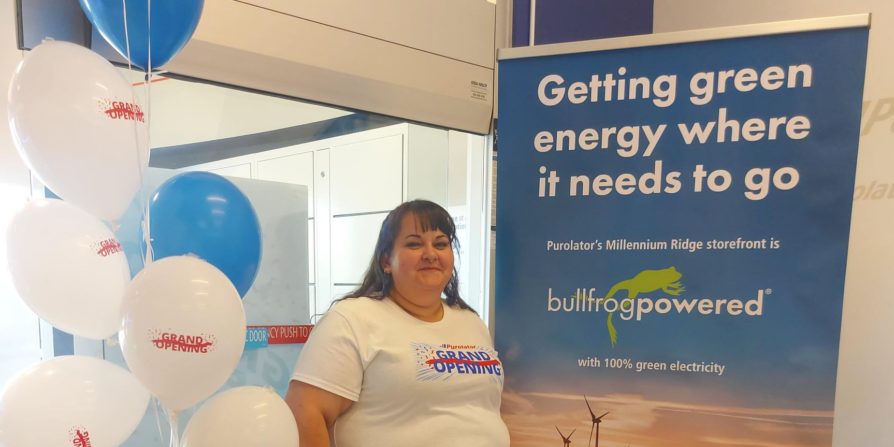 Woman standing beside a Bullfrog Power sign and balloons