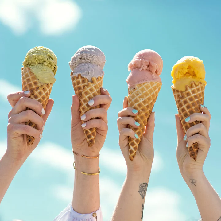 Hands holding ice cream cones on a sunny day