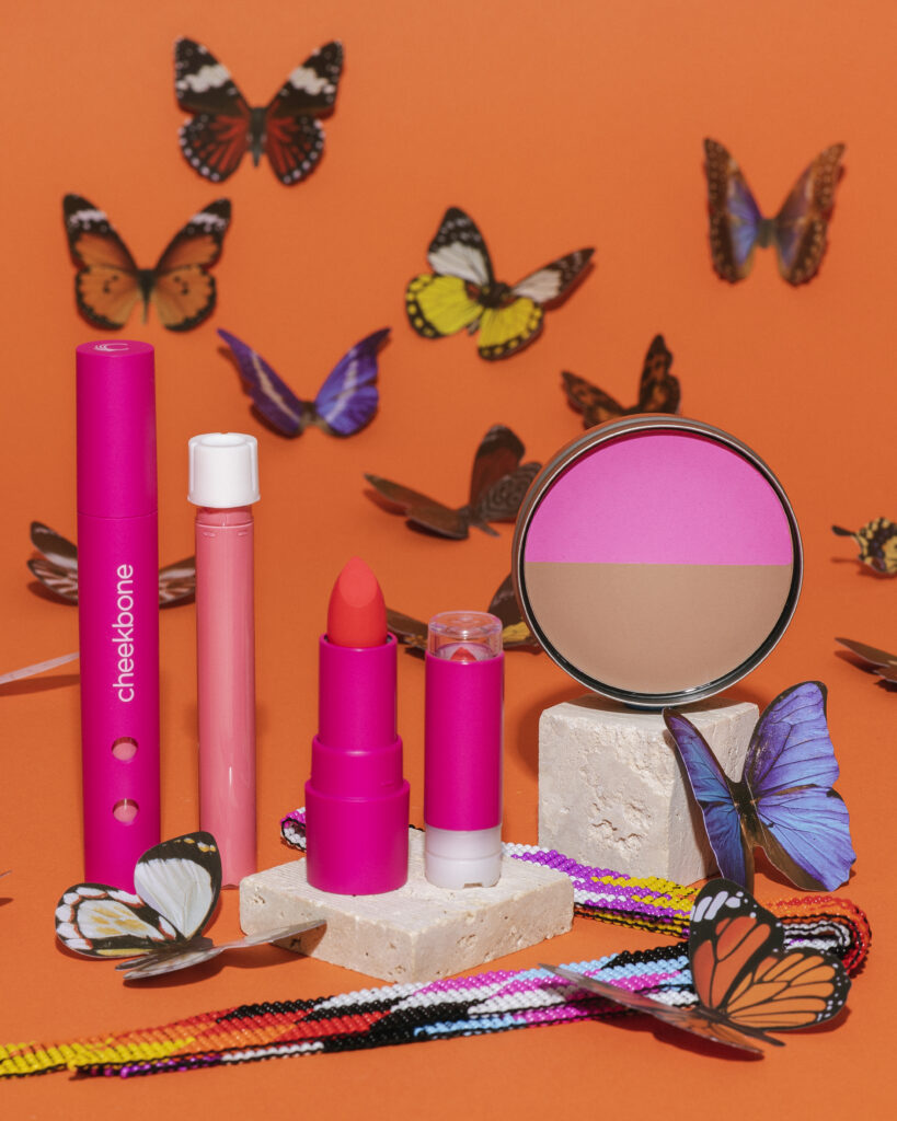 Cheekbone Beauty makeup against a colourful backdrop filled with butterflies.