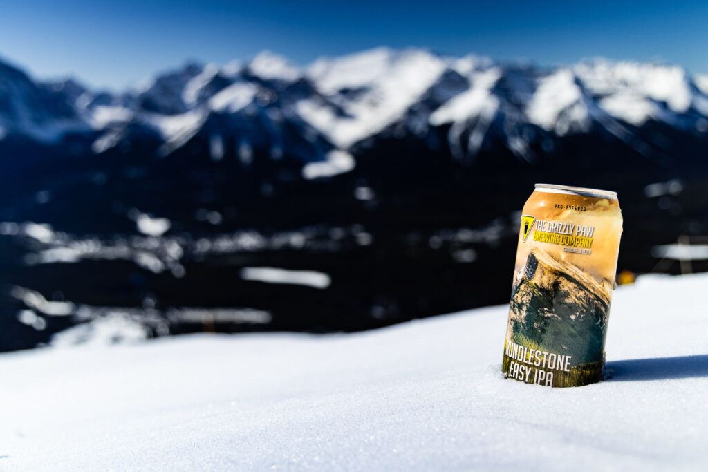 A can of Grizzly Paw Pub and Brewing Company beer against a mountain backdrop