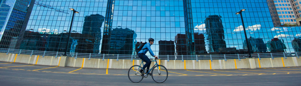 A person riding a bicycle in front of a high-rise building