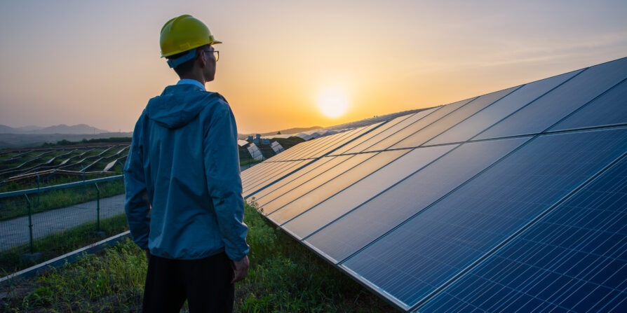 Engineer standing in solar power station looking sunrise
