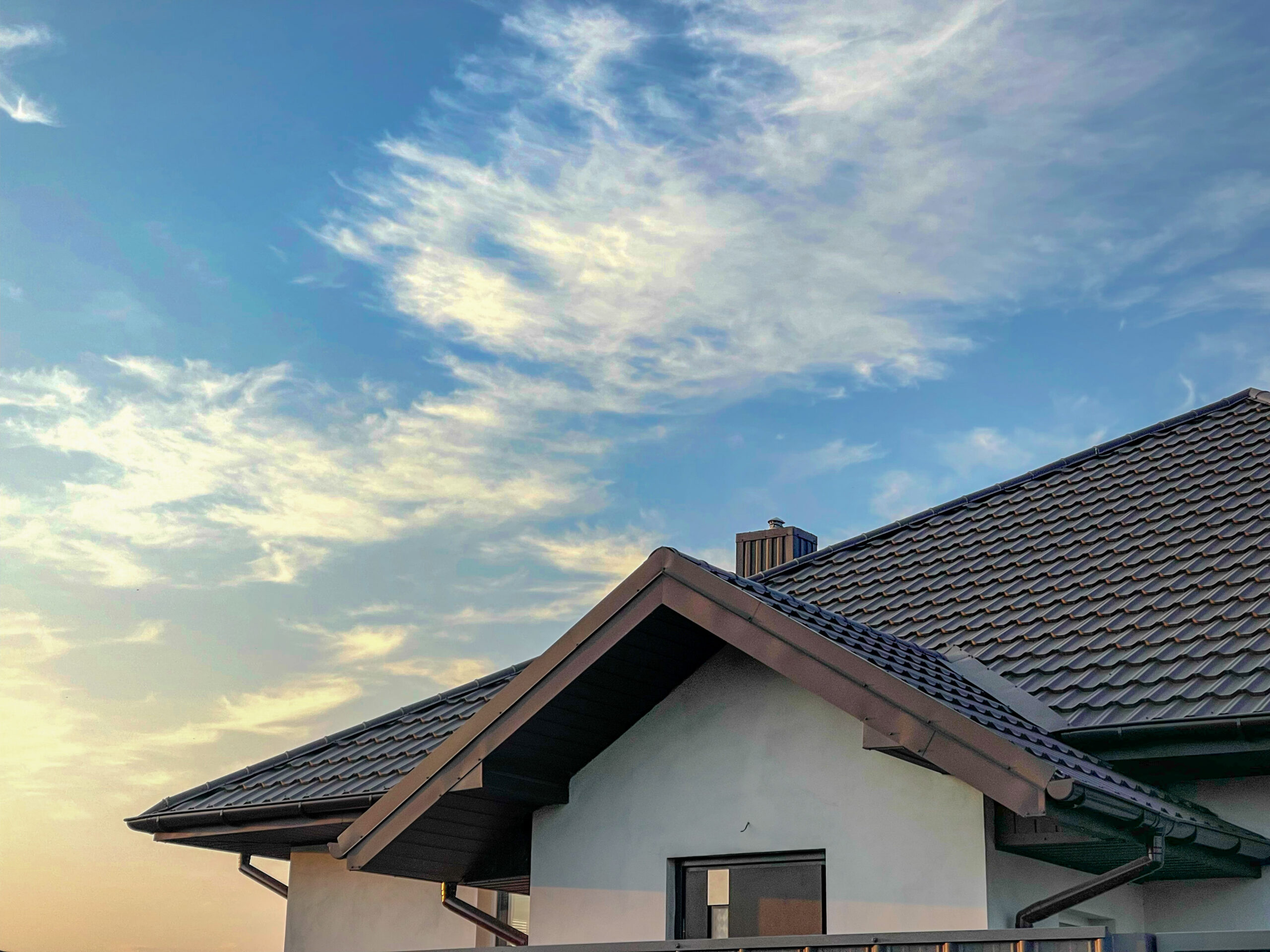 The roof of a home with a blue sunny sky